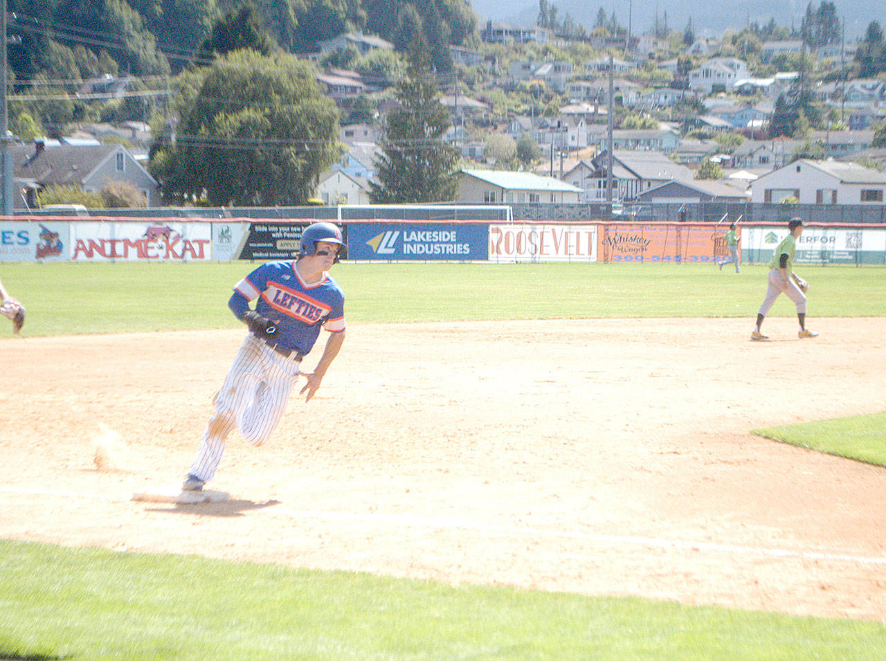 The Lefties’ Nick Oakley rounds third base Sunday at Civic Field on his way to score on a double by Nathan Chong. (Pierre LaBossiere/Peninsula Daily News)