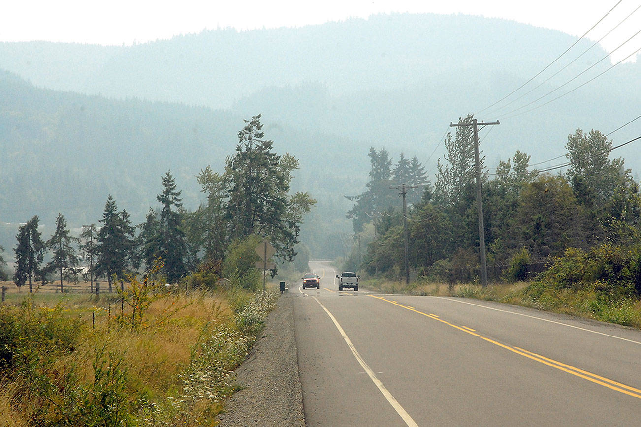 Vehicles make their way down Laird Road west of Port Angeles as a layer of smoke shrouds the Olympic Foothills and the surrounding lowlands on Thursday. (Keith Thorpe/Peninsula Daily News)