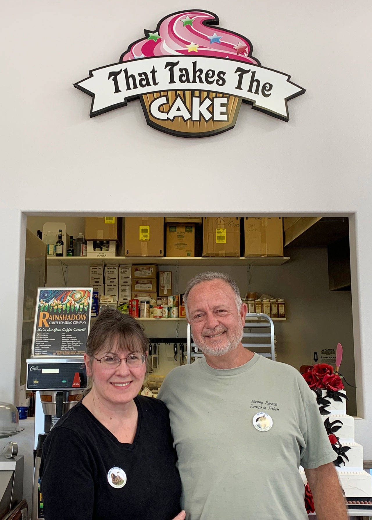 Sue and Paul Boucher of That Takes the Cake in Sequim show off their Olympic Peninsula Tourism Commission “Share” campaign buttons. (Photo courtesy of Olympic Peninsula Tourism Commission)