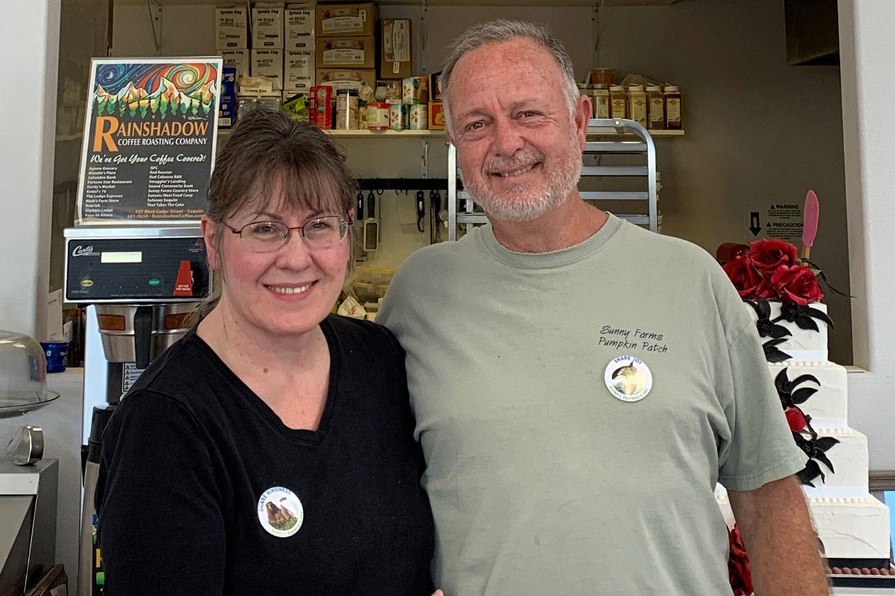 Sue and Paul Boucher of That Takes the Cake in Sequim show off their Olympic Peninsula Tourism Commission “Share” campaign buttons. (Photo courtesy of Olympic Peninsula Tourism Commission)