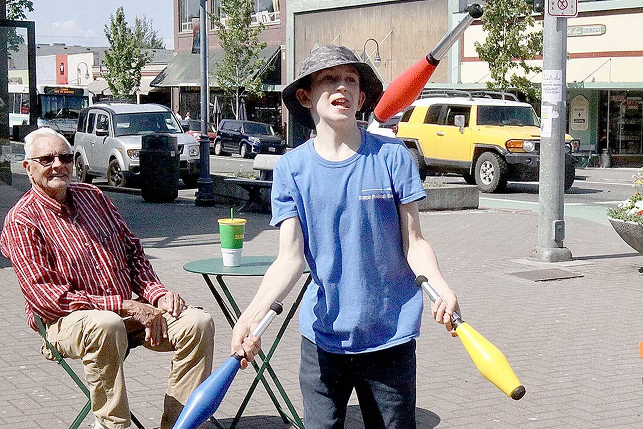 Juggler Charlie Thompson, 13, shows off his stuff to passersby and Gary Ross, sitting in a chair in front of the Conrad Dyer Fountain at First and Laurel streets in Port Angeles. Thompson has been juggling since he was 9 and said he learned most of it from watching YouTube. He rides his bike downtown to entertain locals and visitors alike. (Dave Logan/For Peninsula Daily News)