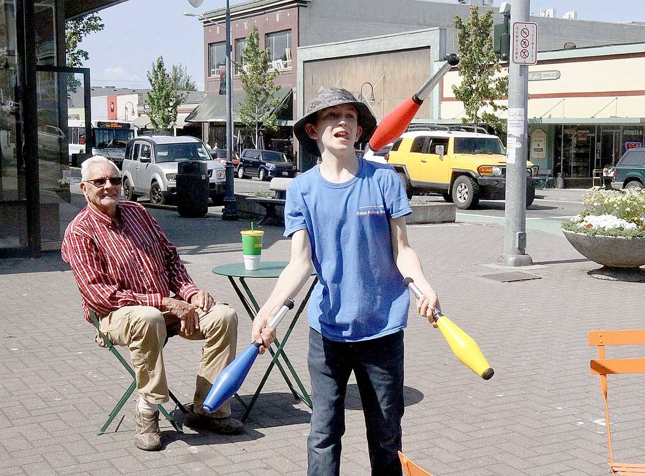 Juggler Charlie Thompson, 13, shows off his stuff to passersby and Gary Ross, sitting in a chair in front of the Conrad Dyer Fountain at First and Laurel streets in Port Angeles. Thompson has been juggling since he was 9 and said he learned most of it from watching YouTube. He rides his bike downtown to entertain locals and visitors alike. (Dave Logan/For Peninsula Daily News)