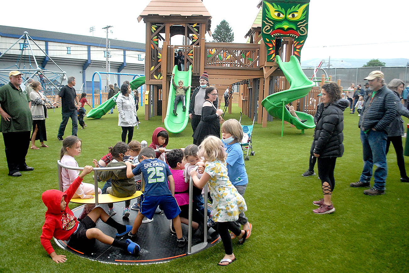Keith Thorpe/Peninsula Daily News
Children cavort on a merry-go-ground after Friday evening's soft opening of the Generation II Dream Playground at Erickson Playfield in Port Angeles.