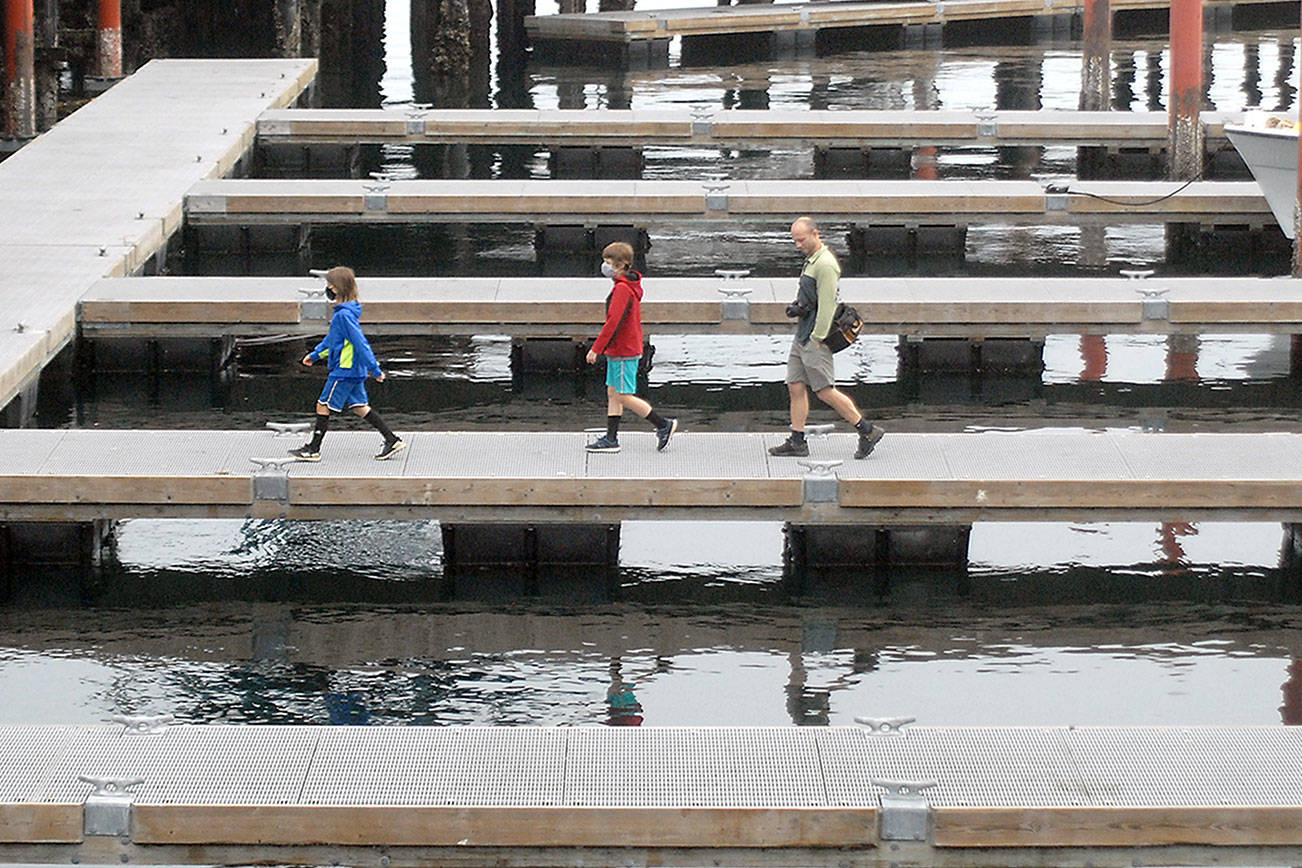 Kyle Dietrich, 9, left, Sam Dietrich, 9, and father Joe Dietrich, all of Toledo, Ore., walk along a floating dock used for transient moorage at Port Angeles City Pier on Thursday. The family was admiring marine life while exploring the pier area. (Keith Thorpe/Peninsula Daily News)