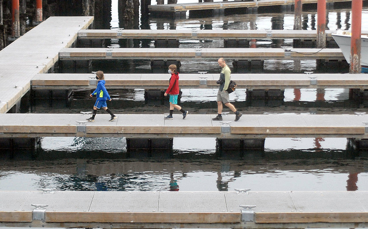 Kyle Dietrich, 9, left, Sam Dietrich, 9, and father Joe Dietrich, all of Toledo, Ore., walk along a floating dock used for transient moorage at Port Angeles City Pier on Thursday. The family was admiring marine life while exploring the pier area. (Keith Thorpe/Peninsula Daily News)