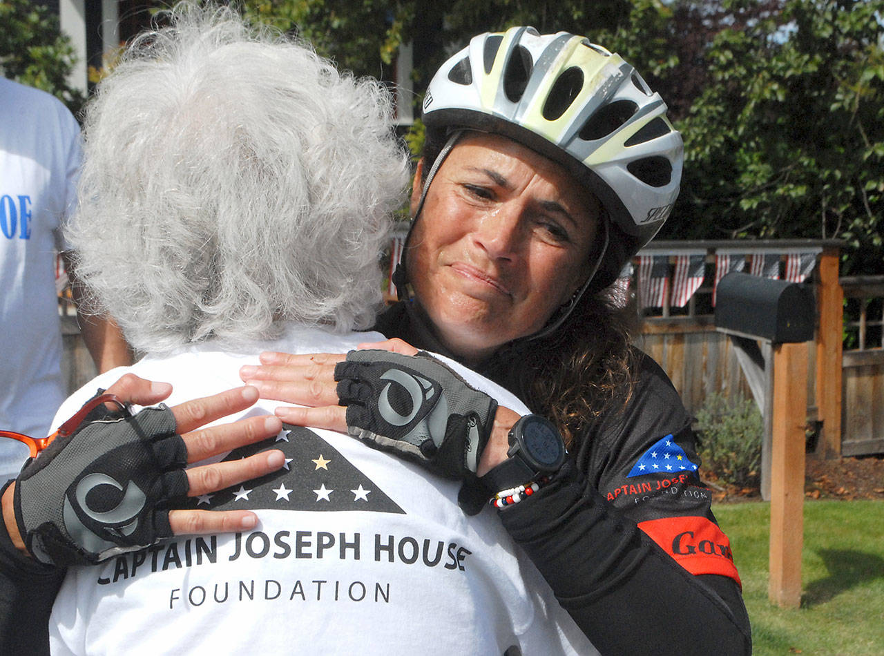 Special education kindergarten teacher Amy DelaBarre of Port Angeles gives an emotional hug to Betsy Schulz, founder of the Captain Joseph House Foundation in Port Angeles, after DelaBarre completes the bicycle portion of Run for Joe, a solo triathlon on Saturday to raise funds in support of Gold Star families who have lost loved ones in military action. The Captain Joseph House, a former bed and breakfast, which was converted to give respite to military families, is named for Schultzs son, Joseph Schultz, who was killed in action in Afghanistan on May 29, 2011. (Keith Thorpe/Peninsula Daily News)