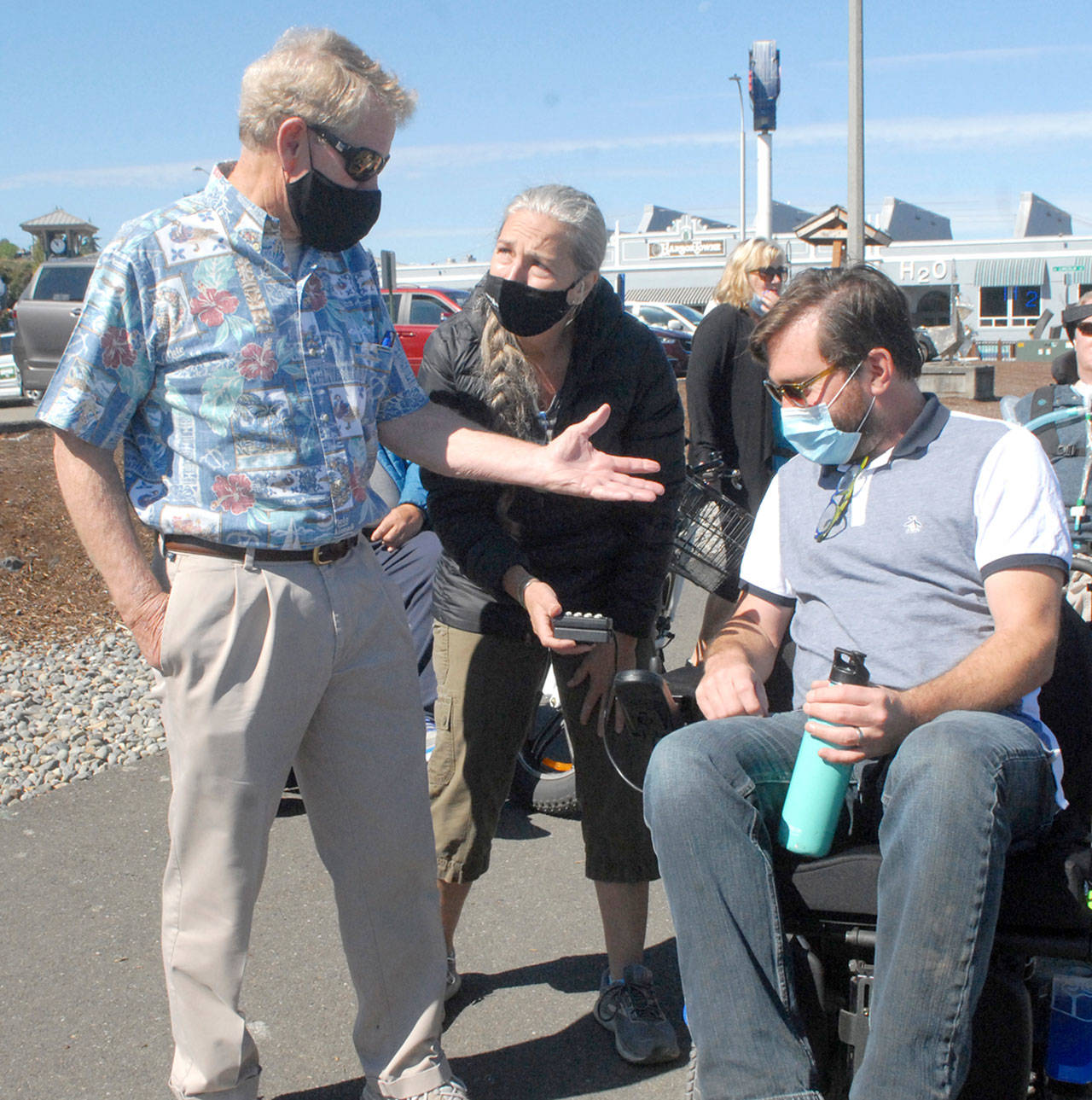 Clallam County Commissioner Randy Johnson, left, speaks with Jefferson County Commissioner Greg Brotherton, seated, as the pair receive motorized wheelchair advice on Saturday from Teena Woodward, mother of Ian Mackay, founder of Ian’s Ride. (Keith Thorpe/Peninsula Daily News)