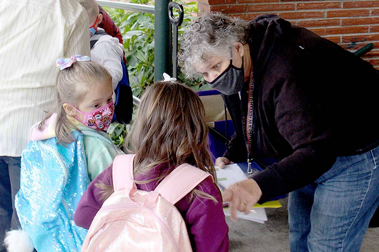 Paraeducator Ginni Beard, right, hands out breakfast bags to kindergarten students during the first day of school for Quilcene School District. Quilcene and Brinnon school districts both began instruction Monday, with COVID-19 prevention protocols, including mask wearing and social distancing for students and staff. (Zach Jablonski/Peninsula Daily News)