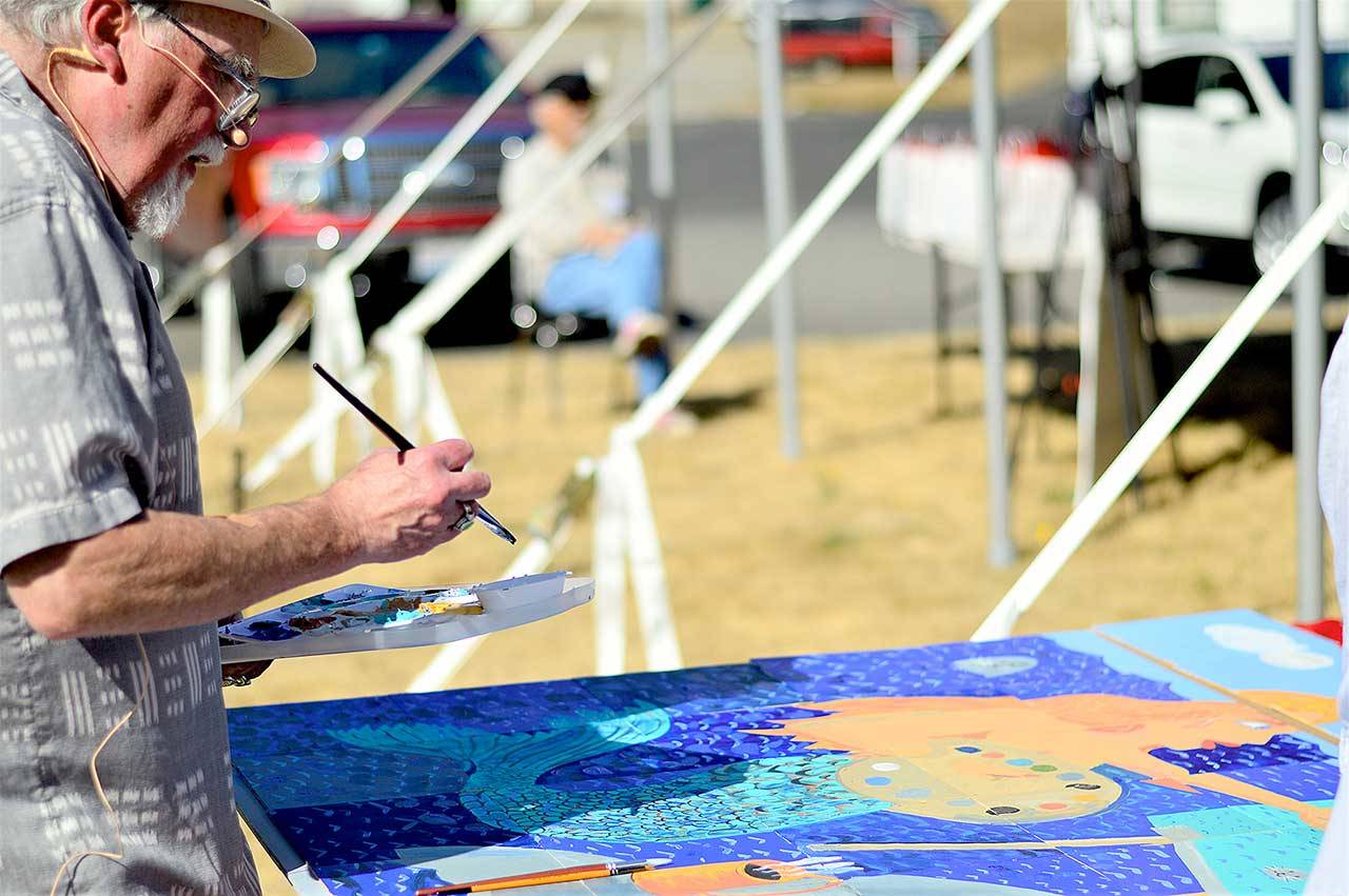 Port Townsend artist and teacher Max Grover finishes up the collective painting he facilitated during “The Big Reveal,” Northwind Art’s fundraiser at Fort Worden State Park on Sunday. (Diane Urbani de la Paz/Peninsula Daily News)