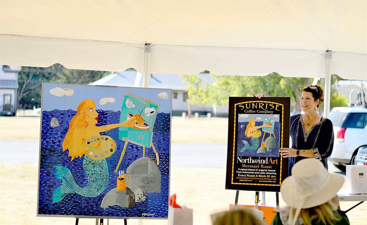 Northwind Art Executive Director Teresa Verraes shows off the just-finished collective painting at the close of “The Big Reveal,” the fundraiser held at Fort Worden State Park on Sunday. (Diane Urbani de la Paz/Peninsula Daily News)