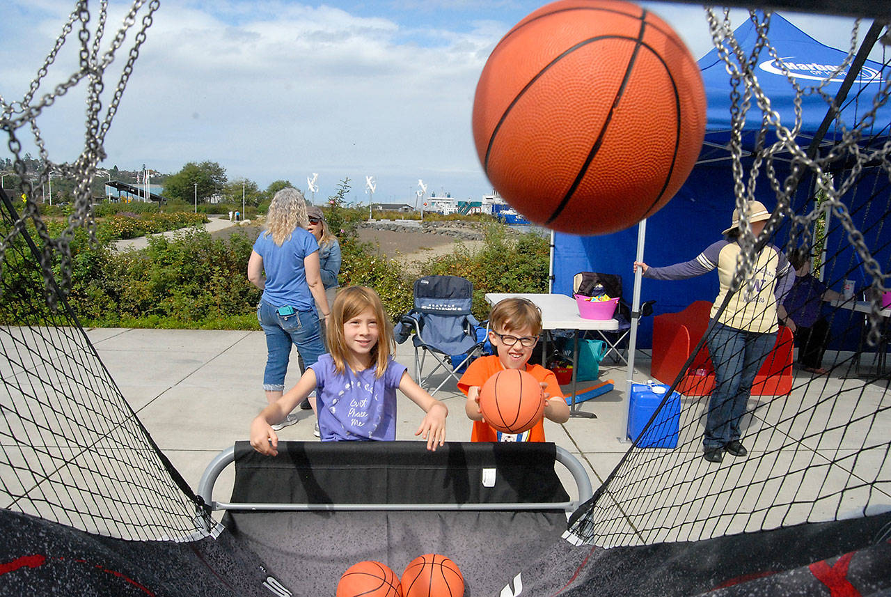 Cousins Ivy Bishop, 7, of Bellingham, left, and Maeve Caron, 6, of Portland, Ore., toss basketballs during a hoops game set up at Pebble Beach Park in Port Angeles during the 2019 Jammin’ in the Park. (Keith Thorpe/Peninsula Daily News)