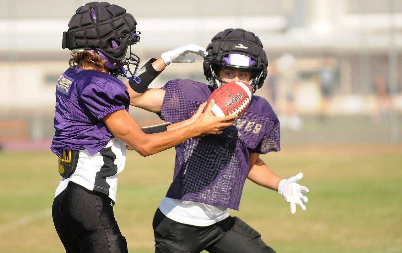 Sequim senior quarterback Kobe Applegate, left, prepares to hand off the football to Aiden Gockerell during a recent practice. The Wolves visit Forks tonight at 7 p.m. in the season opener for each school. (Michael Dashiell/Olympic Peninsula News Group)
