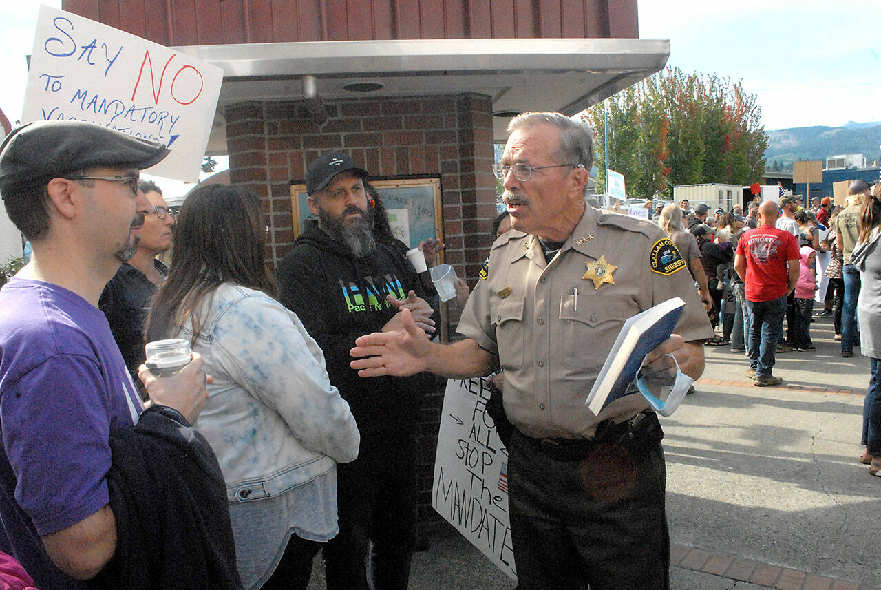 Clallam County Sheriff Bill Benedict, center, talks with vaccination mandate protesters at the main entrance of the courthouse on Friday. (Keith Thorpe/Peninsula Daily News)