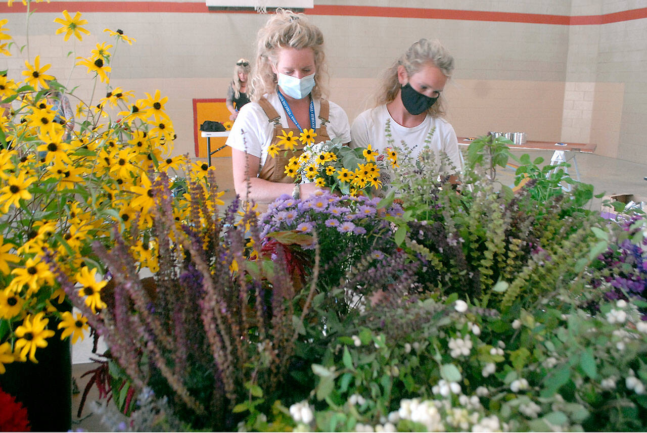 Sisters Jenny Edwards, left, and Julia Ahrndt, both of Port Angeles, assemble flower bouquets that will be distributed to teachers and staff members of the Port Angeles School District at an assembly session with volunteers on Thursday at Hamilton School.