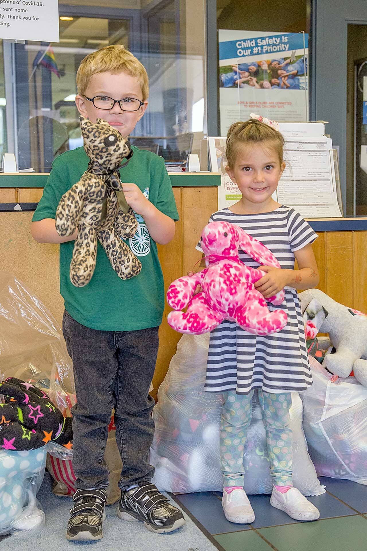 Nick, 5, and Josie, 4, of Great Futures Preschool, housed at the Sequim unit of the Boys & Girls Clubs of the Olympic Peninsula, hold stuffed animals sewn by members of the Sequim Fiber Arts Neighborhood Group of the American Sewing Guild for distribution at the club. (Emily Matthiessen/Olympic Peninsula News Group)