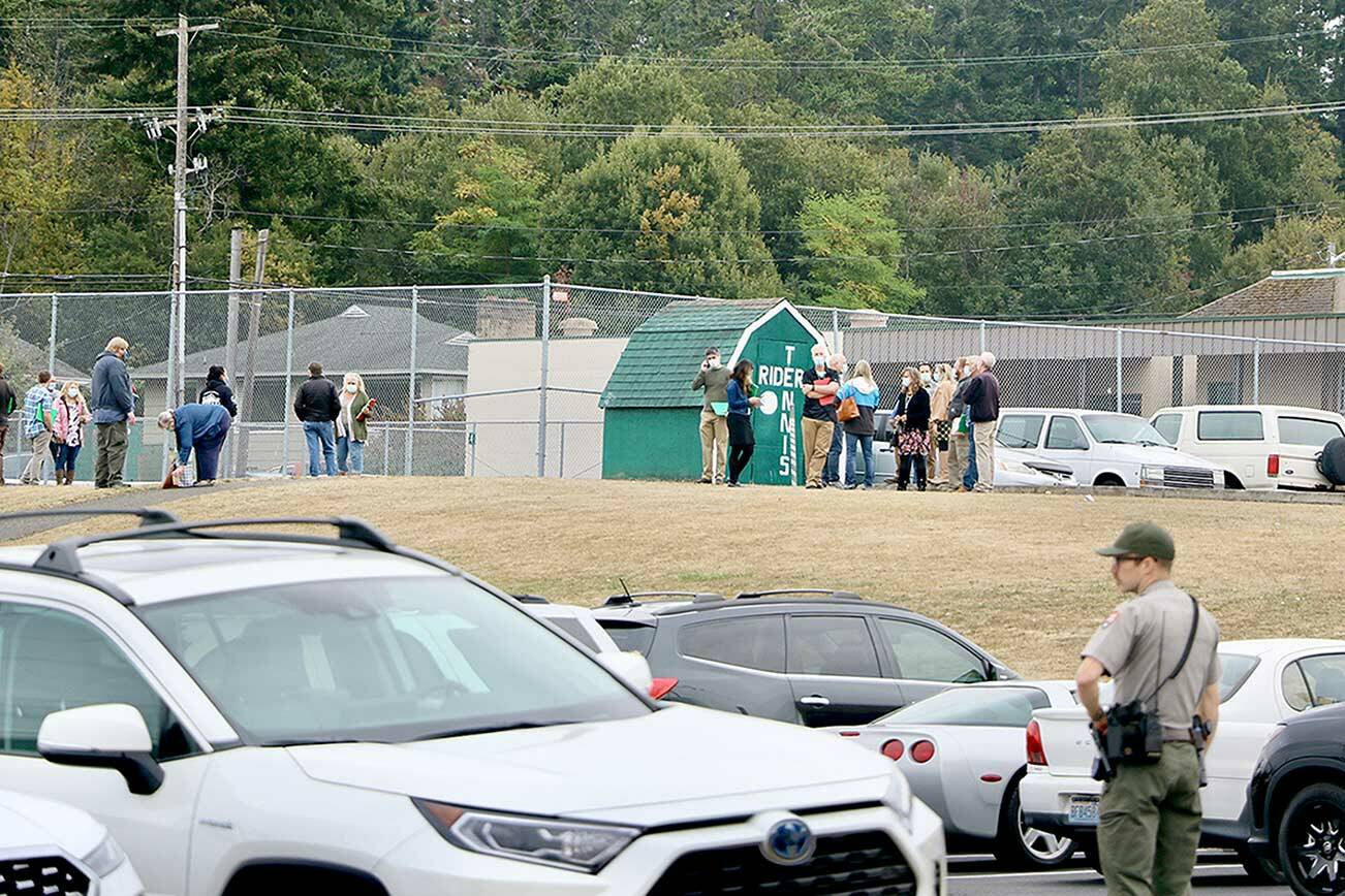 Port Angeles High School faculty and staff wait by the tennis courts on campus for further instructions after students were evacuated from the building on Tuesday. (Ken Park/Peninsula Daily News)