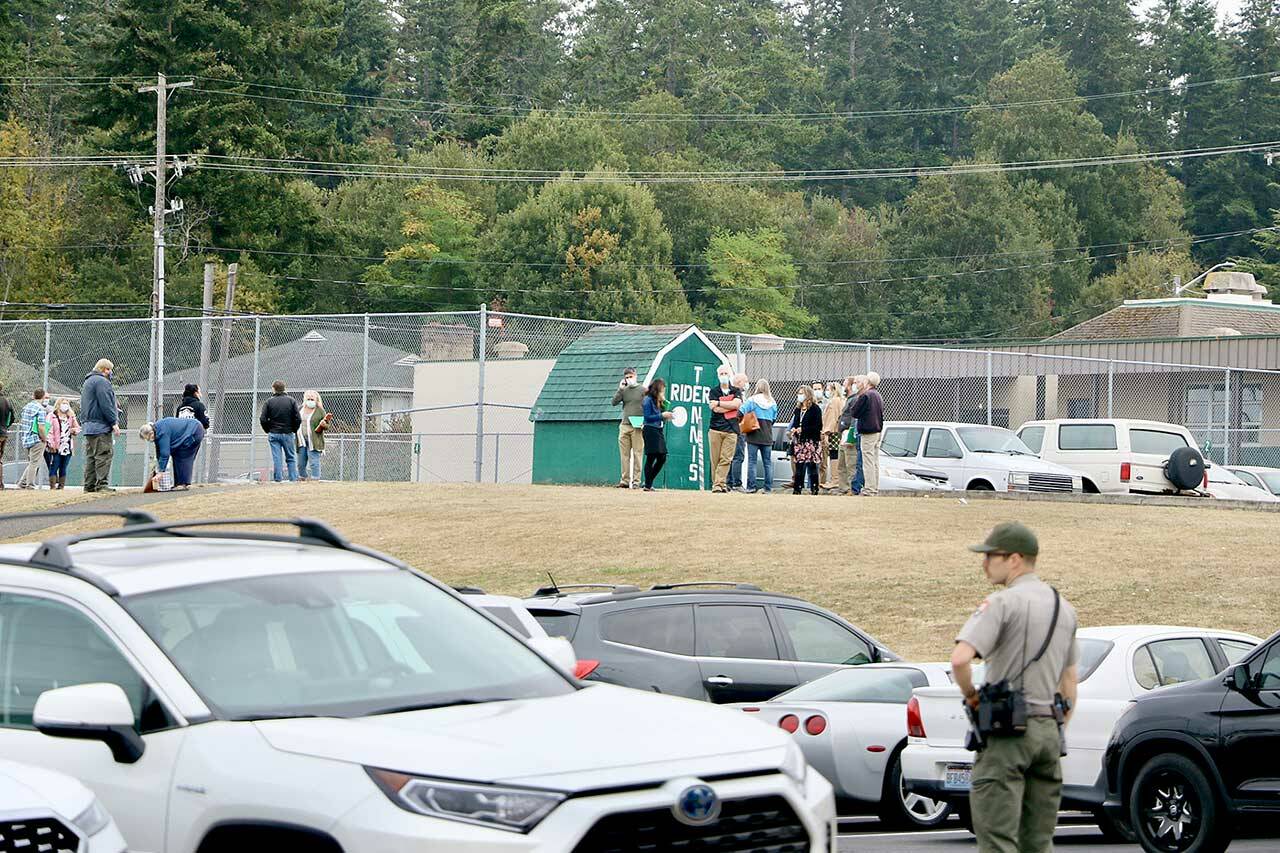 Port Angeles High School faculty and staff wait by the tennis courts on campus for further instructions after students were evacuated from the building on Tuesday. (Ken Park/Peninsula Daily News)