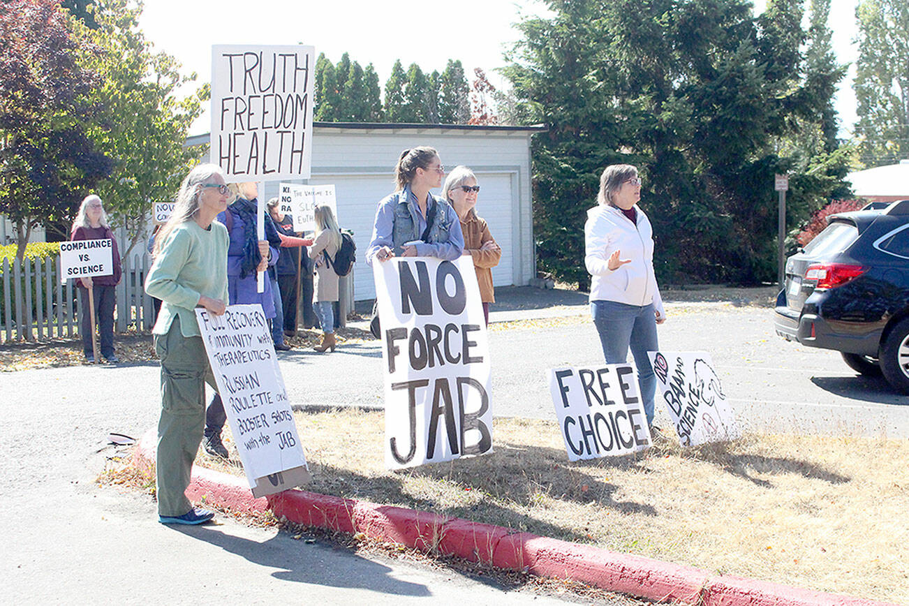 About 10 anti-vaccination protestors gather outside the Port Townsend High School campus Wednesday afternoon, holding a variety of signs such as "the vaccine is slow euthanasia" and equating getting the COVID-19 vaccine to playing a game of Russian roulette. (Zach Jablonski/Peninsula Daily News)
