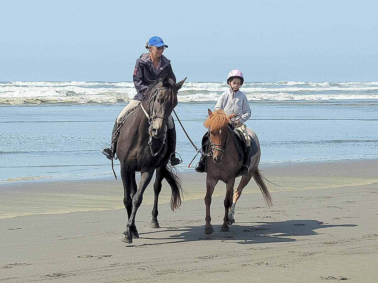 Mary Gallagher helps the younger sister of one her Advanced Hoof Beats students, Daniela Dam, riding Chili Pepper, acclimate to riding on a wide open beach rather than an enclosed arena. (Photo by Kimi Robertson)