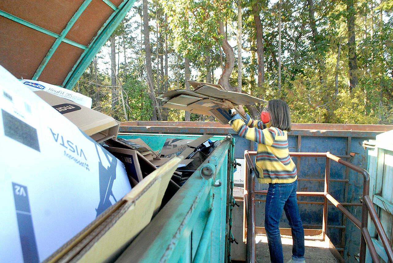 Yvette Stepp of Sequim places cardboard in a recycling bin on Friday at the Port Angeles Regional Transfer Station. (Keith Thorpe/Peninsula Daily News)