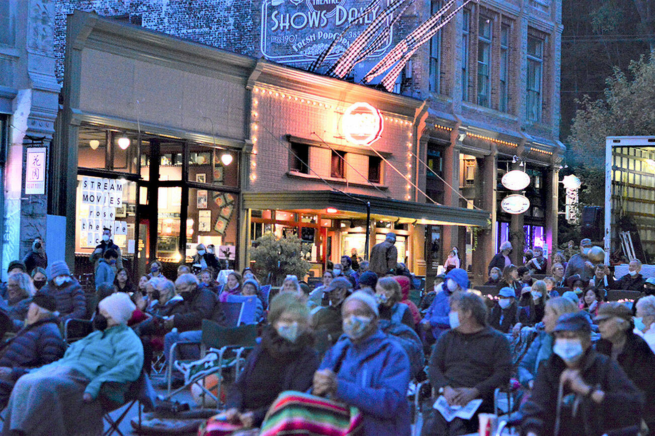 A flock of moviegoers came to see "Lily Topples the World," Friday night's Port Townsend Film Festival outdoor cinema offering. With the Rose Theatre behind them, the crowd watched the documentary on a giant screen erected over Taylor Street in downtown Port Townsend. Diane Urbani de la Paz/Peninsula Daily News