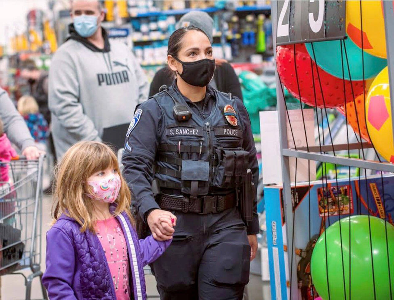 Port Angeles Police Officer Swift Sanchez with a child during a holiday shopping event. The police department is among several agencies in a partnership focused on resiliency throughout October. (Jesse Major Photography)