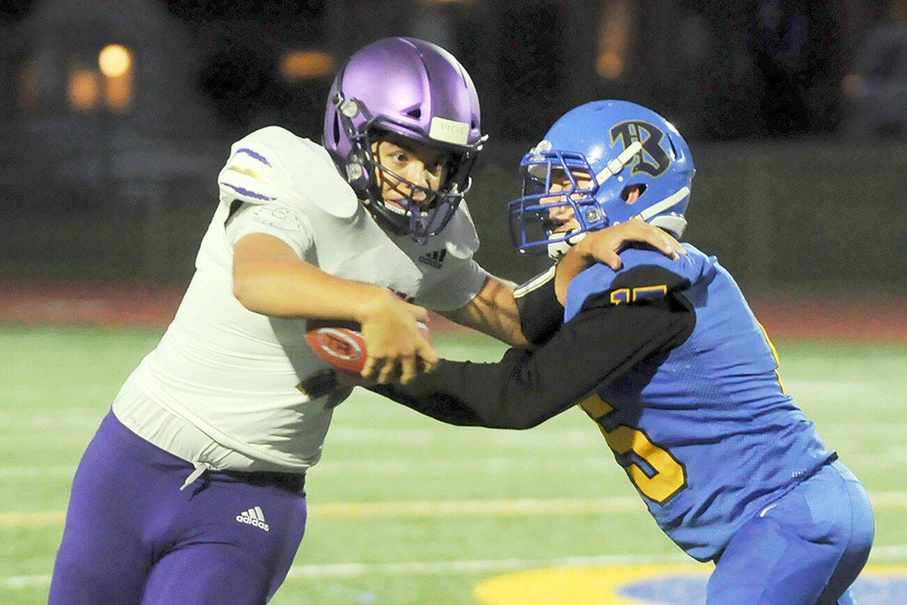 Michael Dashiell/Olympic Peninsula News Group
Sequim quarterback Lars Wiker, left, tries to avoid the grasp of a Bremerton defender in the Wolves' 35-29 loss at Bremerton on Thursday.