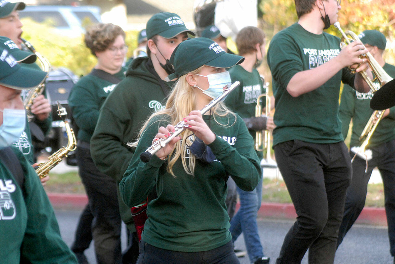 Port Angeles High School sophomore Madeline Irwin, center, plays flute through a hole in her mask with other members of the school’s marching band at the start of Friday’s homecoming parade from the Clallam County Courthouse to Port Angeles Civic Field. The Port Angeles Roughriders were defeated by the Kennedy Catholic Lancers 40-7 in Friday night’s football game. (Keith Thorpe/Peninsula Daily News)
