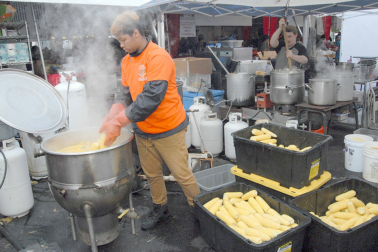 Volunteer corn cook Xavion Mason of Bakersfield, Calif., adds fresh ears to a boiler behind the scenes at the 2019 Dungeness Crab and Seafood Festival. (Keith Thorpe/Peninsula Daily News)