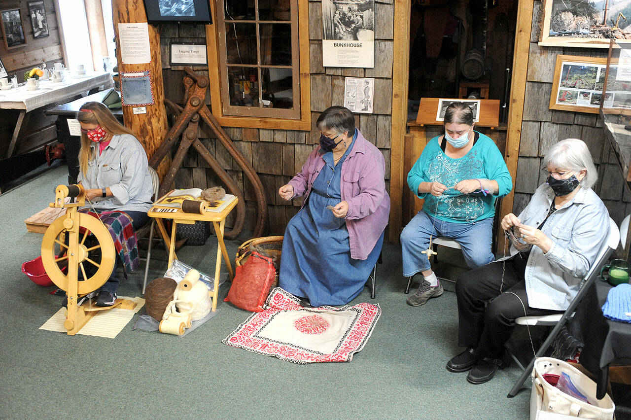 From left, Jennifer Pelikan, Sue Shane, Jessica Mishler, and Linda Offutt are shown Saturday morning at the Forks Timber Museum demonstrating spinning, knitting and sewing. (Lonnie Archibald/For Peninsula Daily News)