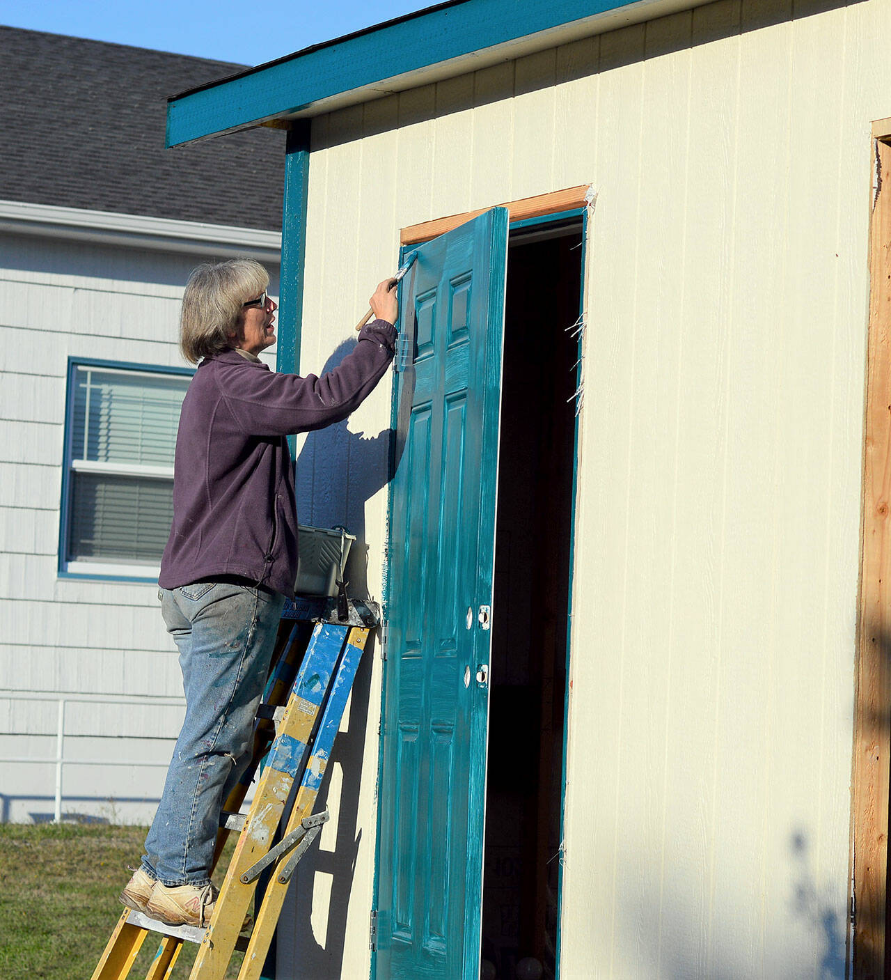 Volunteer Sandy Tweed, a fine artist in Port Townsend, finishes painting a door to the Pat’s Place bathroom unit on Friday. (Diane Urbani de la Paz/Peninsula Daily News)