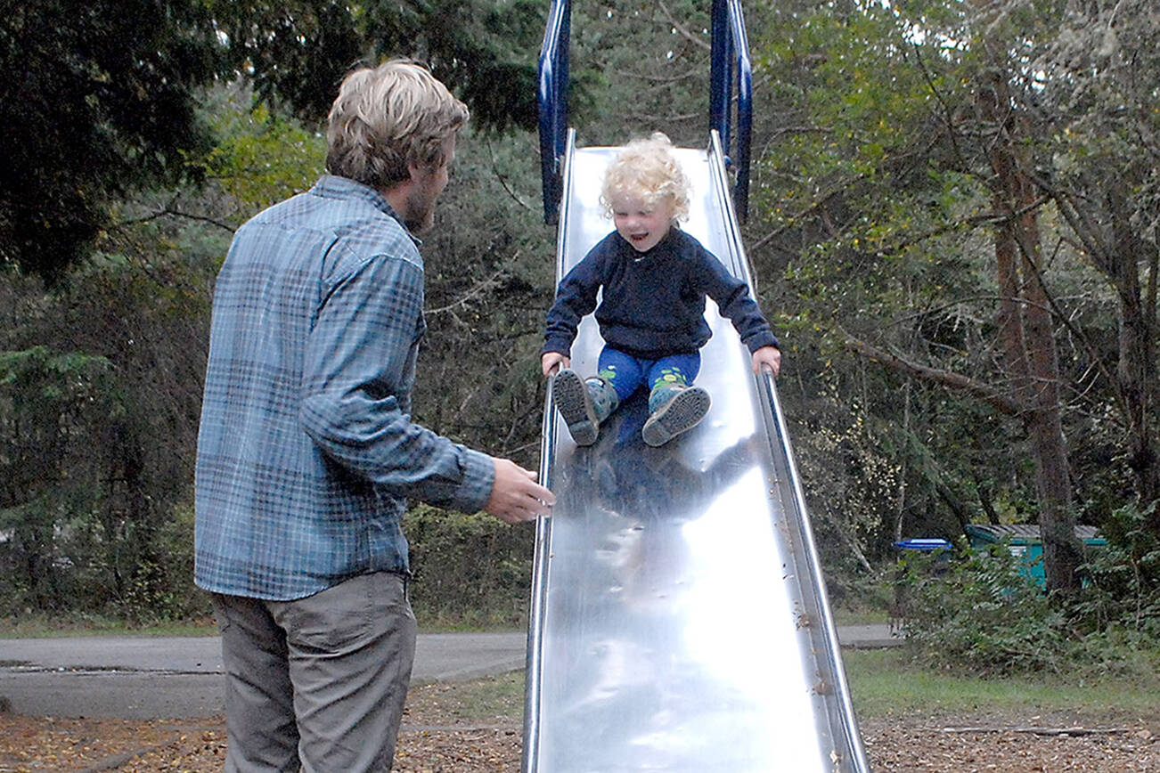 Keith Thorpe/Peninsula Daily News
Glen Wade of Port Angeles encourages his son, Yuli Schutz-Wade, 2 1/2, to go down a tall slide on Thursday on the playground at Dungeness Recreation Area north of Sequim. The area is a popular spot to camp and hike, and provides access to Dungeness Spit and the Dungeness National Wildlife Refuge.