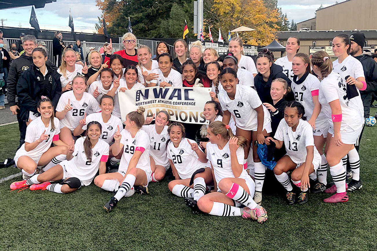 Keith Thorpe/Peninsula/Daily News
Members of the Peninsula College womens soccer team gather around the NWAC North Region championship banner after clinching the top spot in the division with Wednesday's win over Skagit Valley.