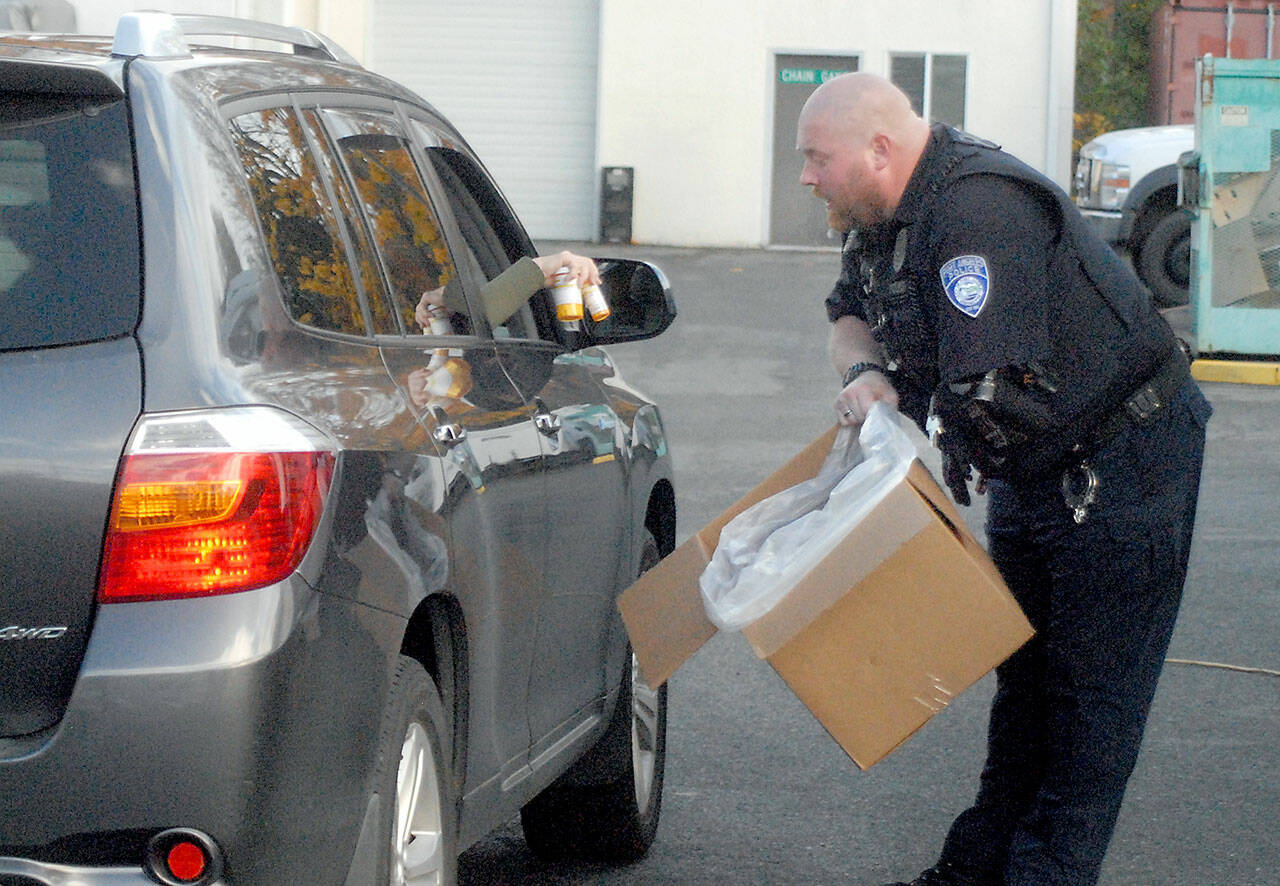 Officer Mike Johnson of the Port Angeles Police Department accepts a drop-off of unwanted drugs on Saturday in the parking lot of the Clallam County Courthouse as part the National Prescription Drug Take Back Day. The annual event, organized by the U.S. Drug Enforcement Administration, allowed people to get rid of potentially dangerous expired, unused and unwanted prescription drugs for safe disposal. (Keith Thorpe/Peninsula Daily News)