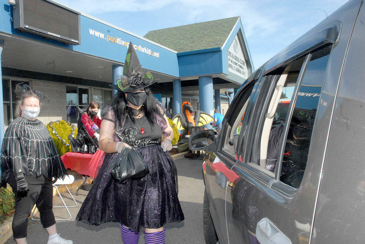 Kayleen McDonald of the Sequim unit of the Boys & Girls Clubs of the Olympic Peninsula delivers bagged lunches to a waiting car as unit director Tessa Jackson, left, looks on during a drive-thru Halloween in front of the organization’s Sequim facility last year. Besides lunch bags, trick-or-treaters were offered hats, treats and coloring books. (Keith Thorpe/Peninsula Daily News)