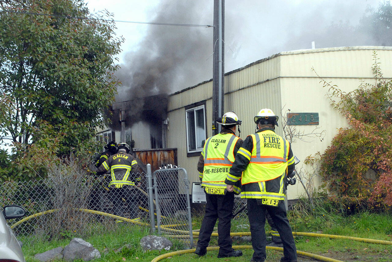 Clallam County Fire District 2 firefighters work to extinguish a blaze in a single-wide house trailer on the 2400 block of East Pioneer Road in Gales Addition east of Port Angeles on Tuesday. (Keith Thorpe/Peninsula Daily News)