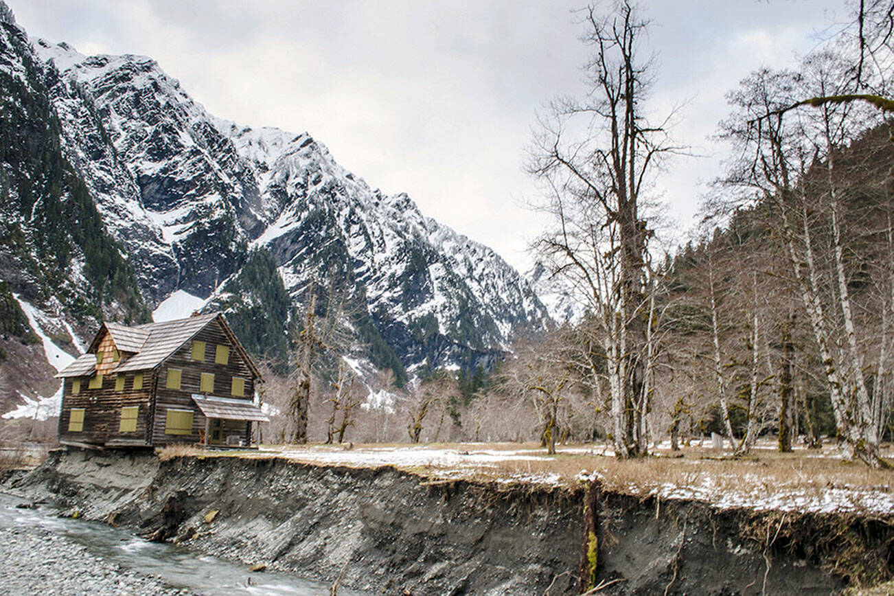 In this April 2014 photo provided by Olympic National Park,  a log cabin teeters on the eroding bank of the Quinault River in Olympic National Park in Washington.  The cabin has been added to the state list of most endangered historical properties.  Built in 1930, the chalet was used as a lodge, summer ranger station and emergency shelter. It's located in the southwest corner of the park, 13 miles up the Graves Creek trail in the Enchanted Valley.  (AP Photo/Olympic National Park)
