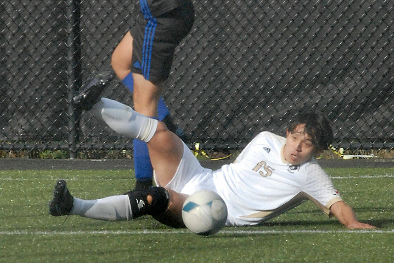 Keith Thorpe/Peninsula Daily News
Peninsula's Chunghwan Lee makes a sliding tackle as Rogue's Josue Reyes avoids a collision on Saturday in Port Angeles.