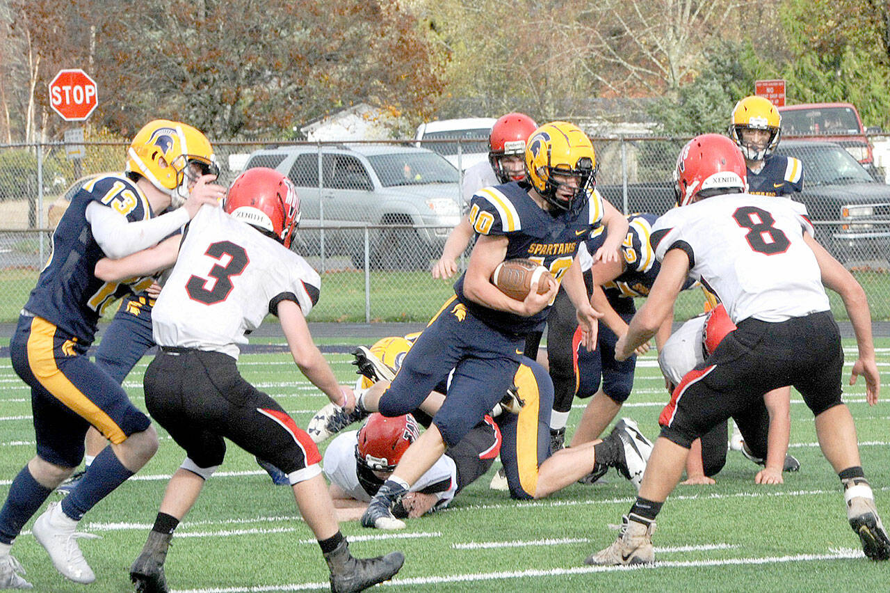 Forks’ Nate Dahlgren makes his cut between Wahkiakum defenders Saturday afternoon in Forks during this 2B playoff game won by the Spartans, 40-14. Dahlgren scored a pair of touchdowns in the win. (Lonnie Archibald/for Peninsula Daily News)