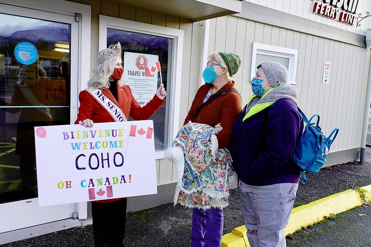 Cherie Kidd, Ms. Senior USA and former mayor of Port Angeles, left, greets Sequim residents Laura and Roman Moore, who want to be part take the first Coho ferry from Port Angeles to Victoria since March 2020. The mother and daughter planned to return immediately on Monday. (Steve Mullensky/for Peninsula Daily News)