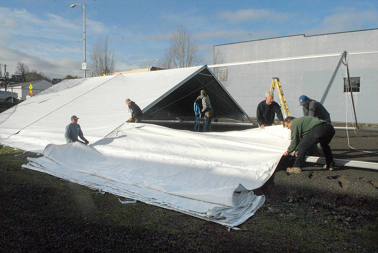 A work crew erects a tent on Wednesday that will cover a temporary ice skating rink to be installed for the annual Winter Ice Village in the 100 block of West Front Street in downtown Port Angeles. Daily ice skating will begin on Nov. 19 and continue through Jan. 3. (Keith Thorpe/Peninsula Daily News)