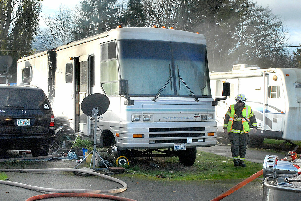 Clallam County Fire District 2 Assistant Chief Dan Huff examines the scene of an RV fire at the Olympic Pines RV Park east of Port Angeles on Wednesday. (Keith Thorpe/Peninsula Daily News)