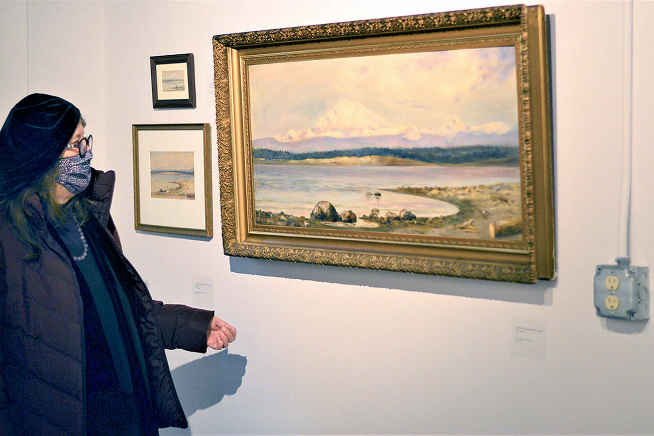Jenny Westdal, Jefferson County Historical Society board president, admires one of Adeline Willoughby McCormack’s paintings in the “Women Outdoors” show at the Jefferson Museum of Art & History. (Diane Urbani de la Paz/Peninsula Daily News)