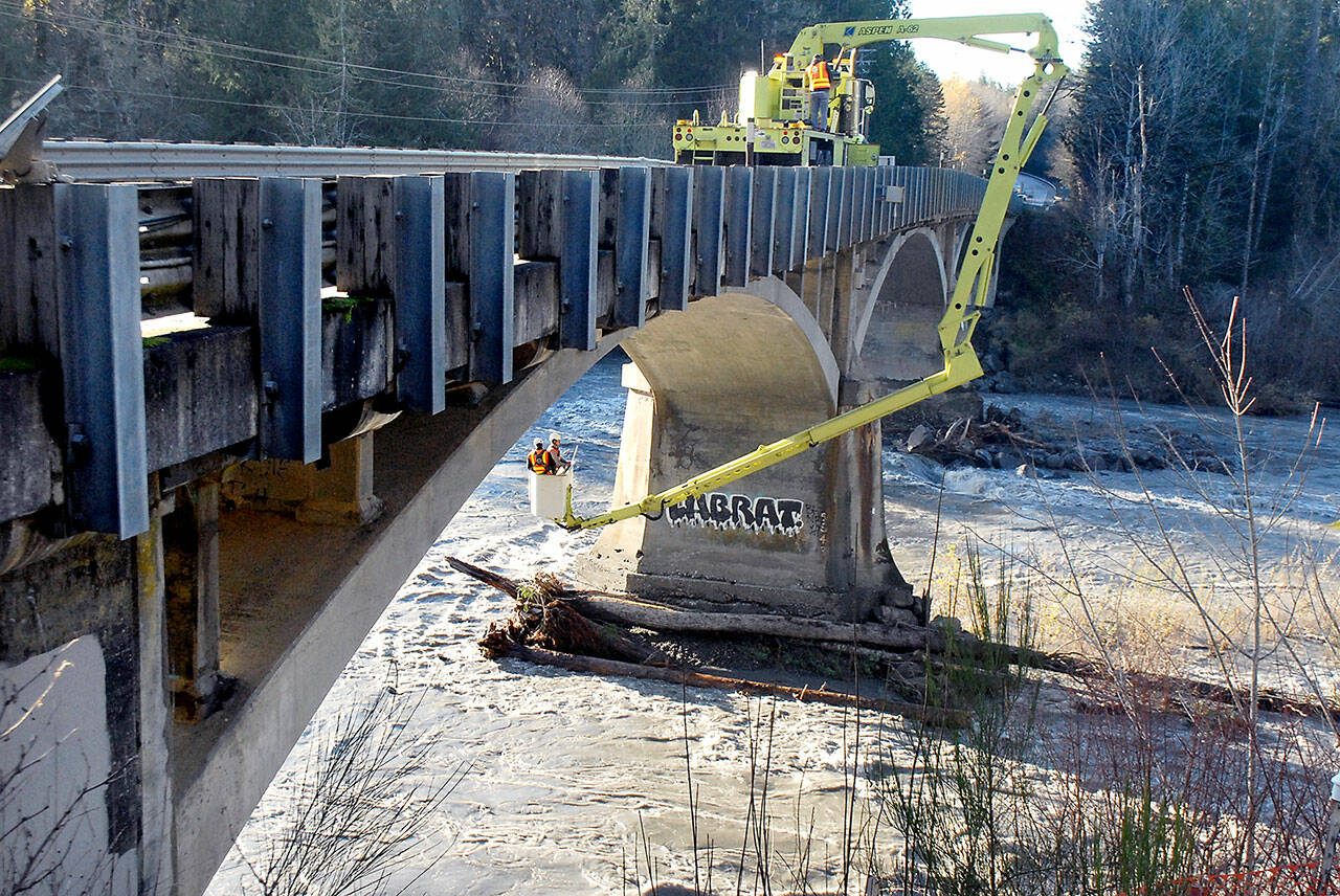 Washington State Department of Transportation bridge inspectors Jim Patton, left, and Mitch Stone examine the bridge supports of the U.S. Highway 101 bridge over the Elwha River on Tuesday after it was closed Monday amid concerns about possible storm damage to the footings. (Keith Thorpe/Peninsula Daily News)
