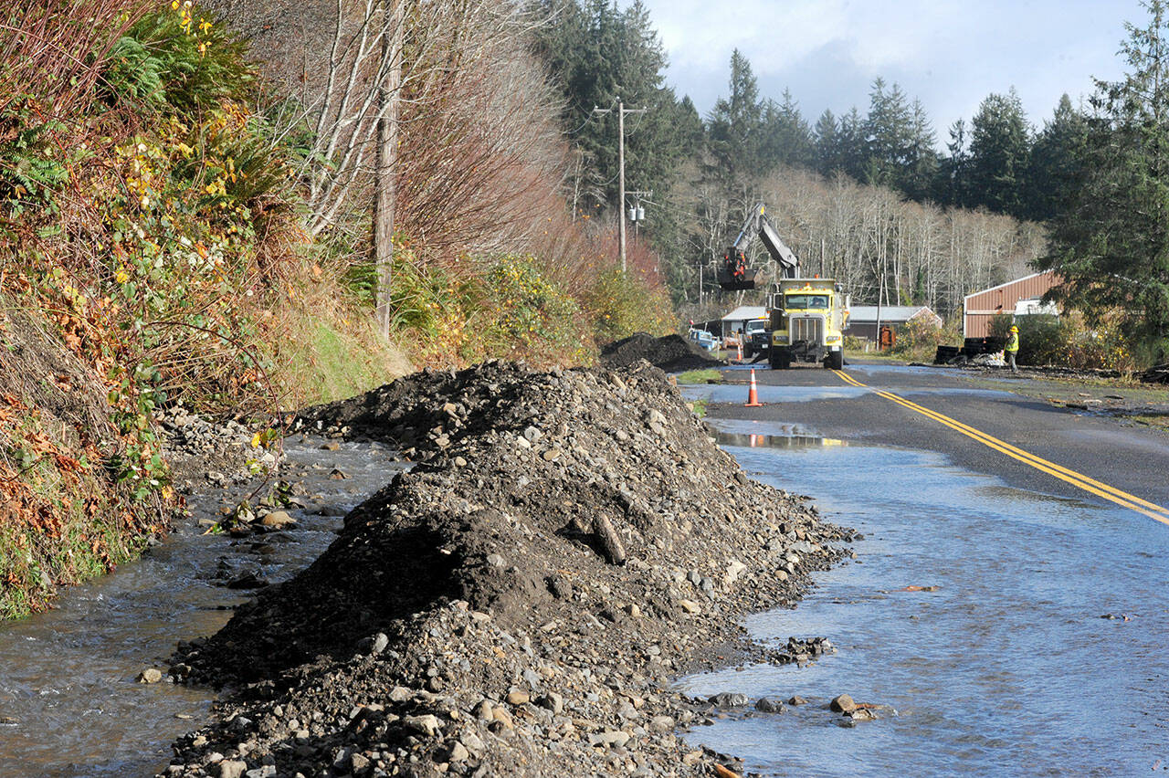 Clallm County road crews work Tuesday to remove debris, which came down several small streams from Tyee Ridge onto the West Lake Pleasant Road in the Beaver area Monday. The road crews worked to reopen the road and are now cleaning up more debris. (Lonnie Archibald/for Peninsula Daily News)