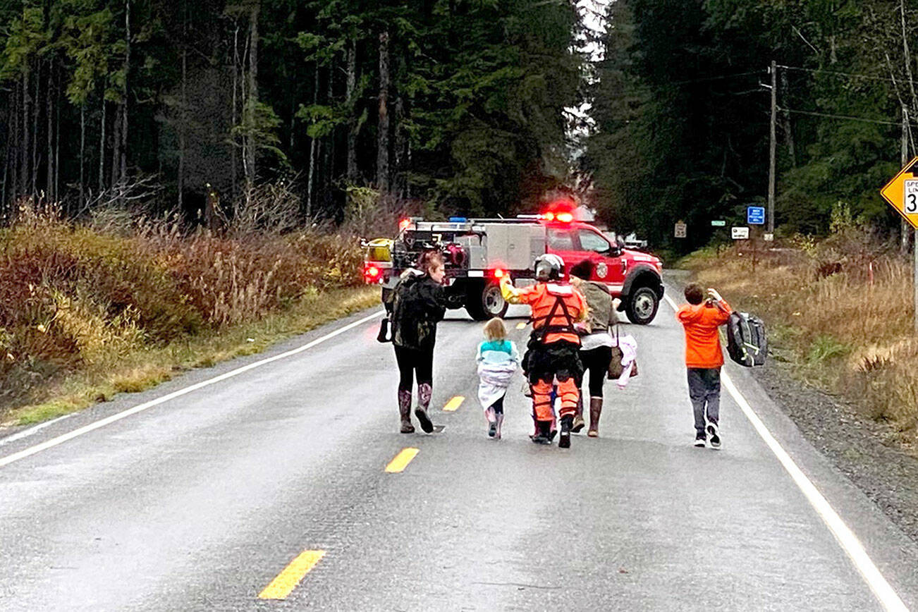 A Coast Guard rescue swimmer escorts multiple people who were evacuated from their residences during a flood near Forks, WA, Monday, Nov. 15. The crew evacuated a total of 10 people, including several children, after receiving a request for assistance from Clallam County emergency responders. (U.S. Coast Guard photo by Sector Columbia River)