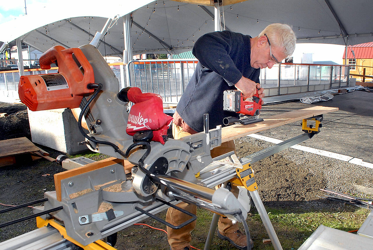 Steve Hargis cuts pieces on Wednesday for a viewing platform for ice skaters at the Port Angeles Winter Ice Village. (Keith Thorpe/Peninsula Daily News)