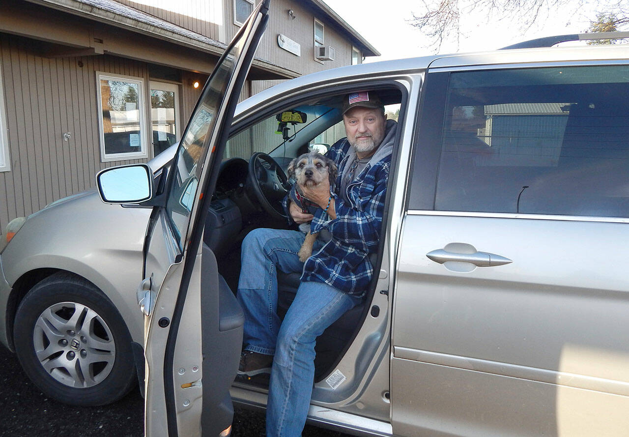 Jerry Harmon and his dog Oliver sit in their temporary home, a van, on Wednesday in Forks. (Christi Baron/Olympic Peninsula News Group)
