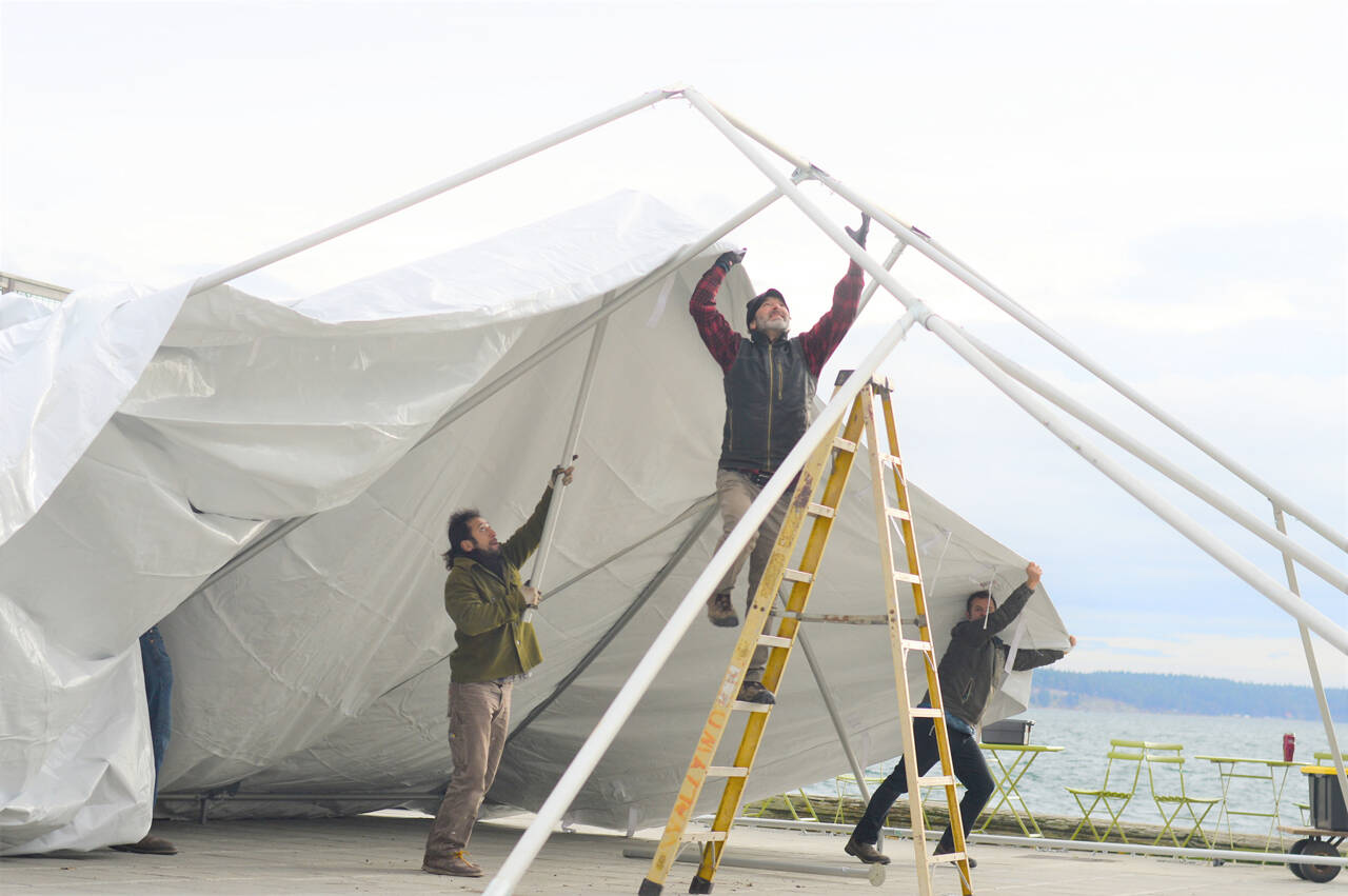 Danny Milholland, right, and Production Alliance crew members Larry Lawrence, on ladder, and Victor Paz raise their 30-foot by 40-foot tent over Port Townsend’s Tyler Street Plaza on Monday morning. The $13,000 tent is rated for 90 mph winds, Milholland said. It will stay tied to 2-ton concrete anchors for five weeks; then the tent will be moved to Pope Marine Park in time for New Year’s Eve festivities downtown. (Diane Urbani de la Paz/Peninsula Daily News)