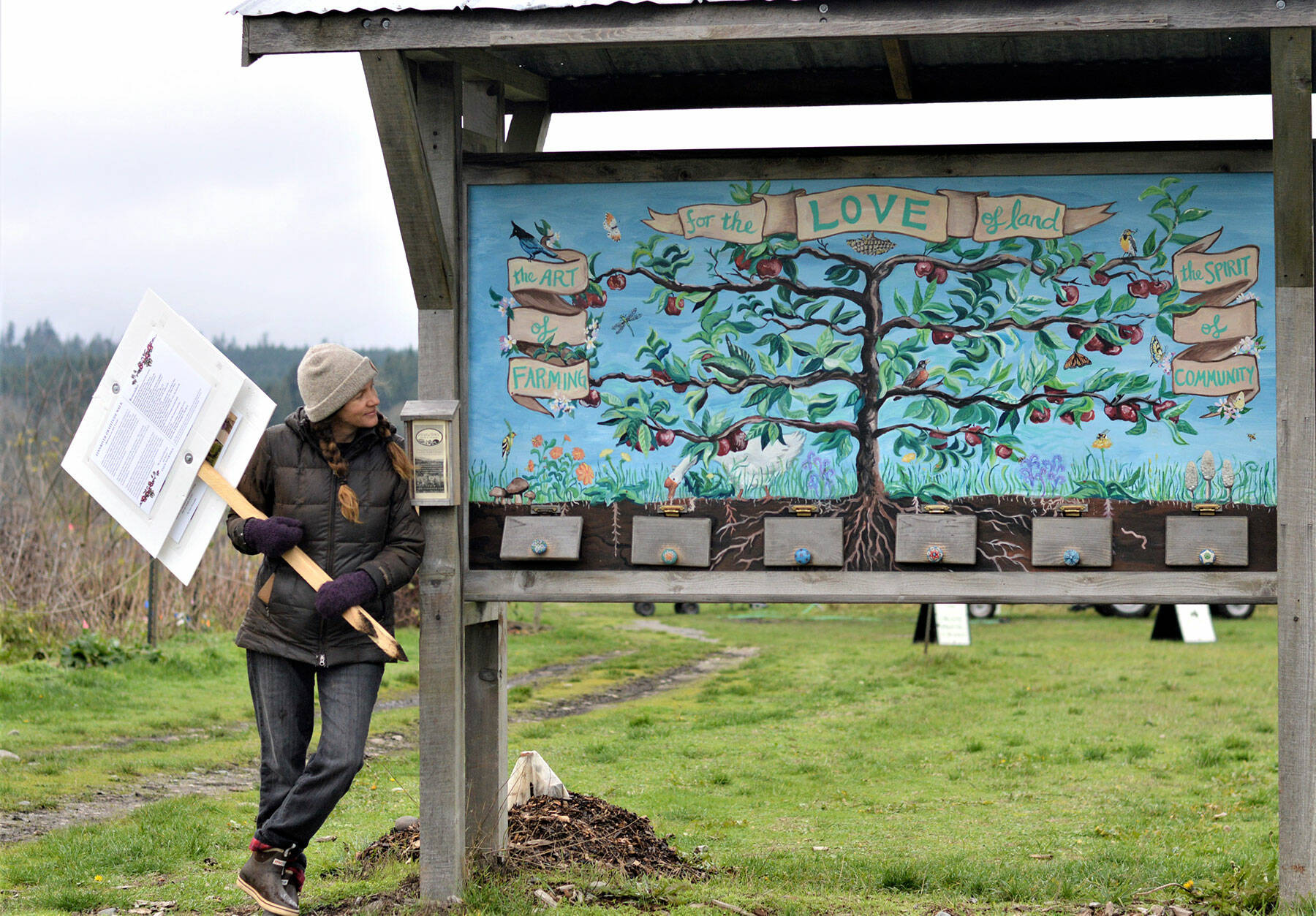 At Chimacum’s Finnriver Farm, cofounder Crystie Kisler admires Kira Mardikes’ painted tribute to the land and its creatures. The painting stands near Finnriver’s “gratitude walk,” part of the farm’s activities today through Sunday. (Diane Urbani de la Paz/Peninsula Daily News)